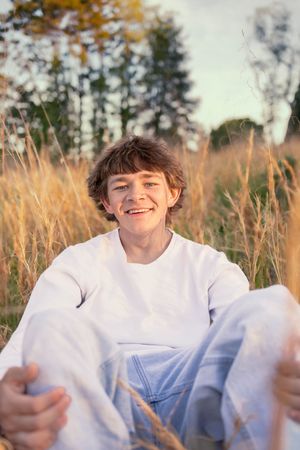 Senior photo in Charlottesville, VA at golden hour in tall grass.
