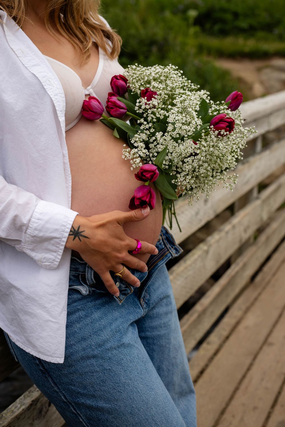 Pink tulips and baby's breath bouquet held against white shirt and denim.