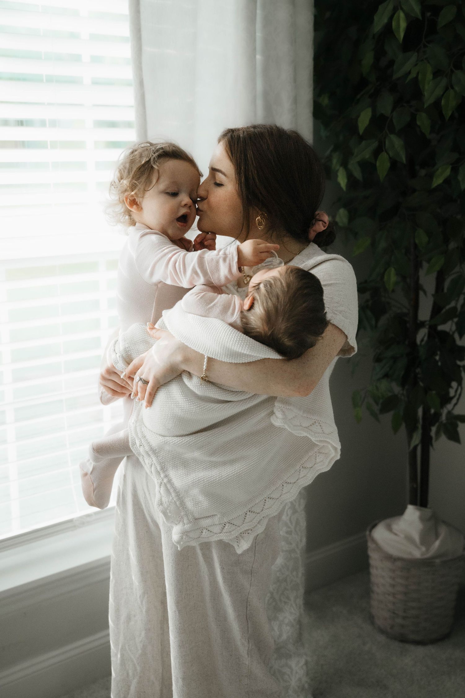 A tender moment between parent and children by a sunlit window.