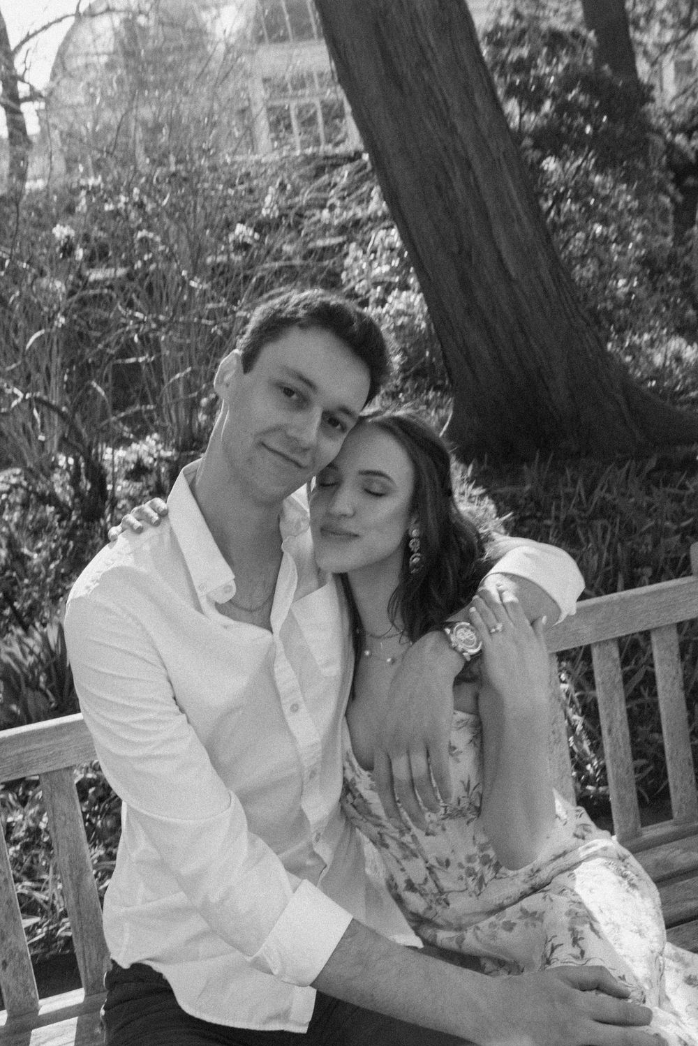 Black and white photo of a couple embracing on a bench in a garden setting.