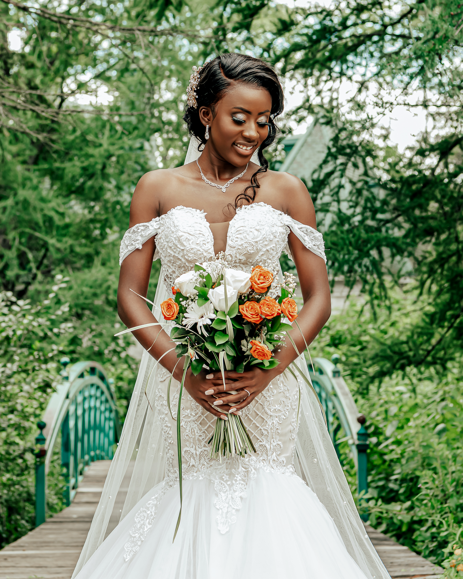 Portrait d'une mariée radieuse sur un pont en nature, portant une robe de mariage élégante et un bouquet coloré capturé par Payo Studio