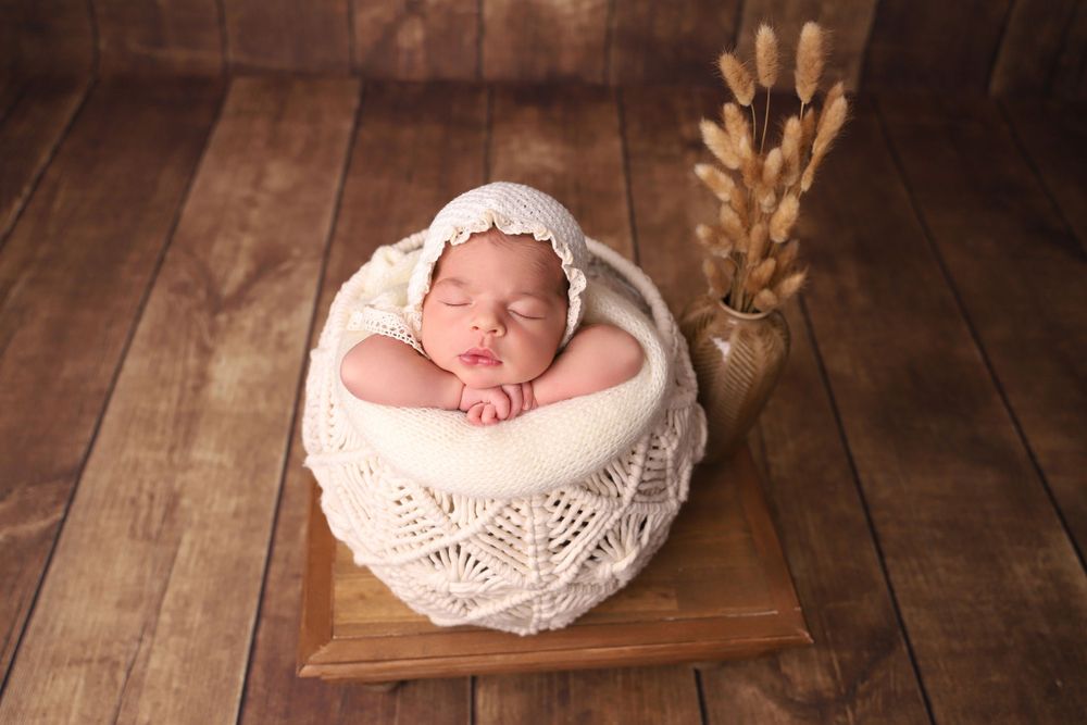 Artistic newborn photography with vintage lace props on dark wooden background.