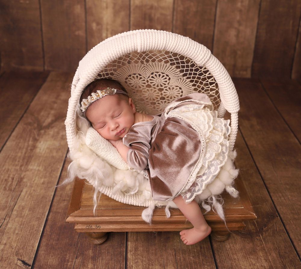 Newborn photography series with white knit basket props on rustic wooden floor.