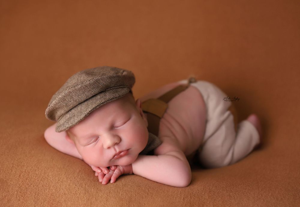 Simple artistic newborn photography on warm brown background with natural lighting.