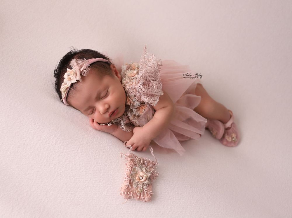 Delicate newborn portraits in soft pink tones on light background.