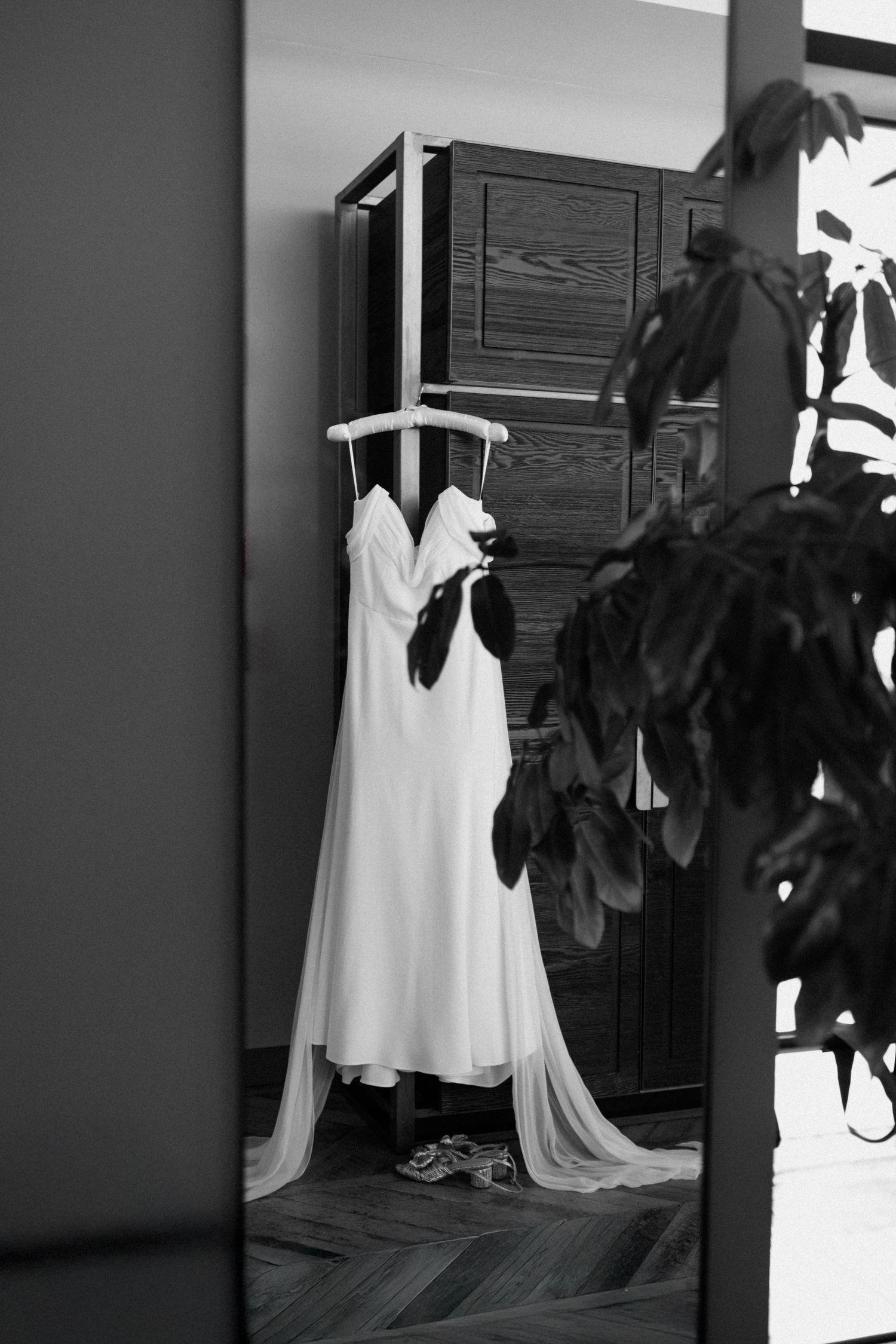 Elegant white wedding dress hanging in a minimalist dressing room.