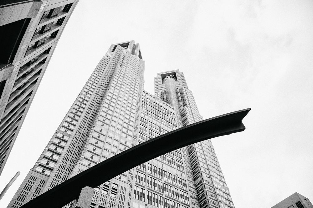 Low angle black and white architectural photographs showing tall skyscrapers against a bright sky in an urban setting.