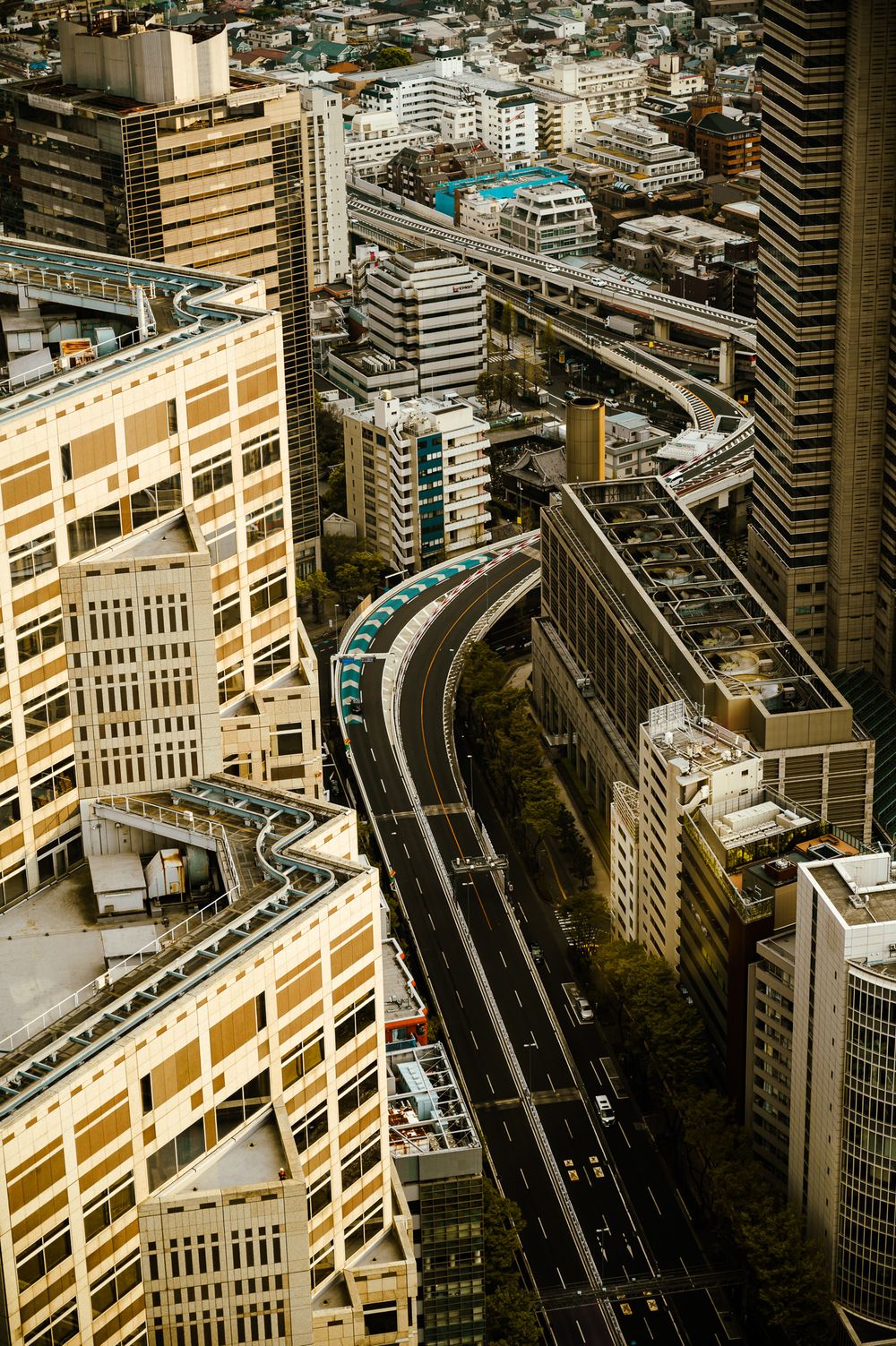 Aerial view of curved elevated railway tracks winding between modern buildings in a dense urban cityscape.