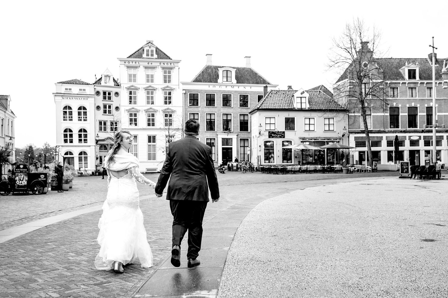Bruidspaar lopend over het plein in Deventer op weg naar de feestlocatie Vrienden van Vroeger