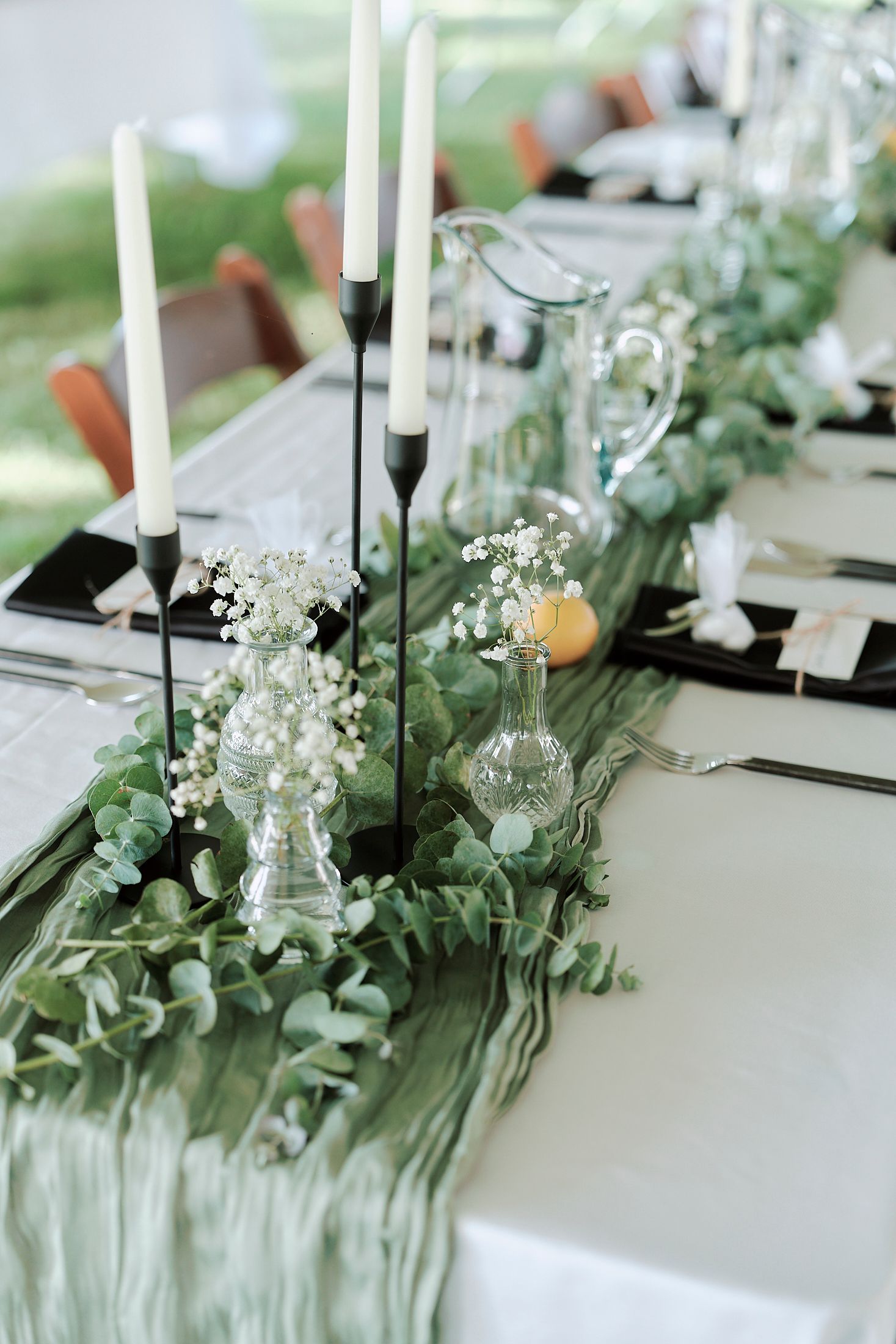Elegant wedding table decor with white flowers, greenery, and black candles.