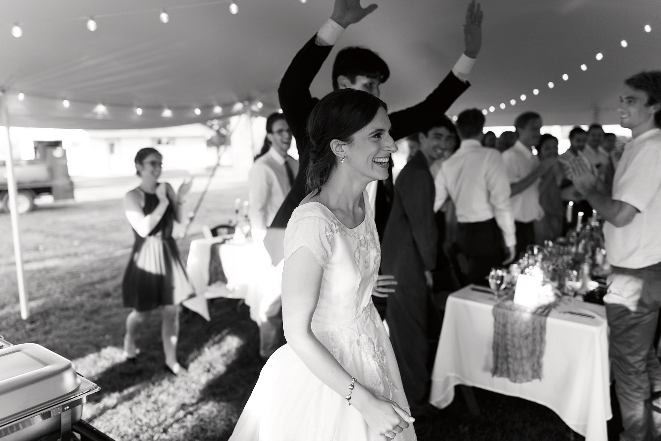 Wedding reception celebration under string lights with guests dancing and mingling on the dance floor.