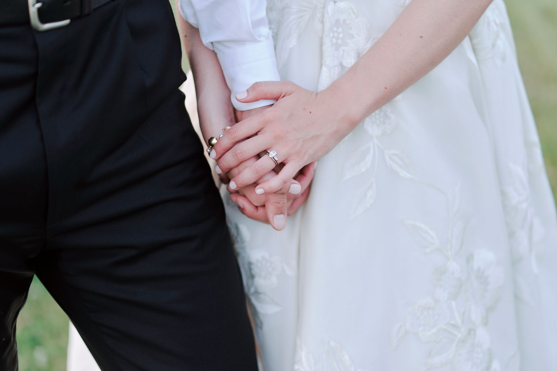 Close-up of formal wedding attire showing hands and dress details.