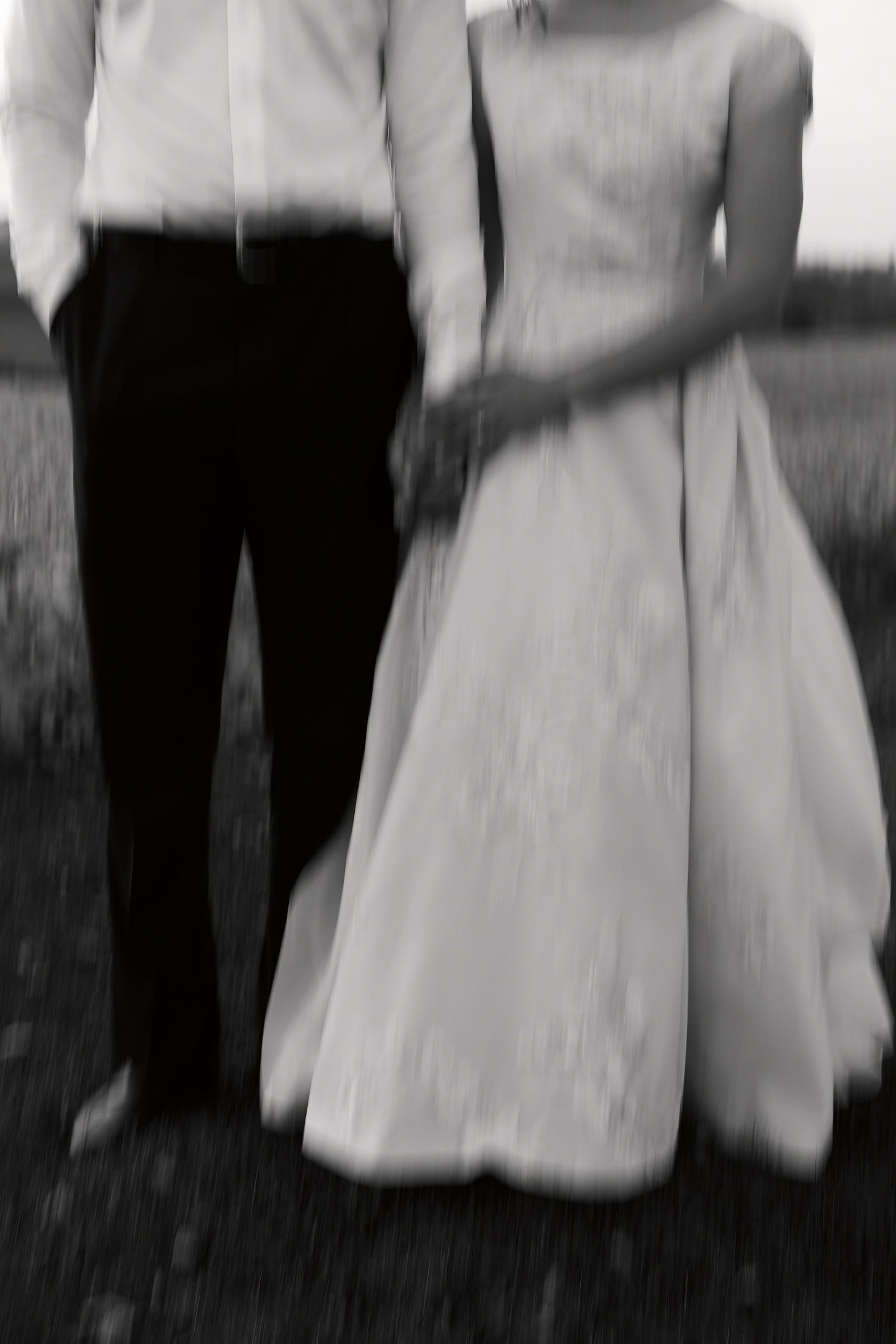 A black and white photograph shows people in formal attire standing together at an outdoor gathering.
