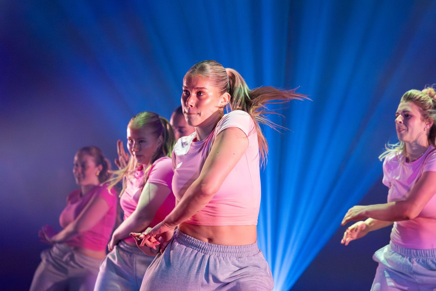 Dancers perform an expressive contemporary dance routine against a dramatic blue-lit stage backdrop.