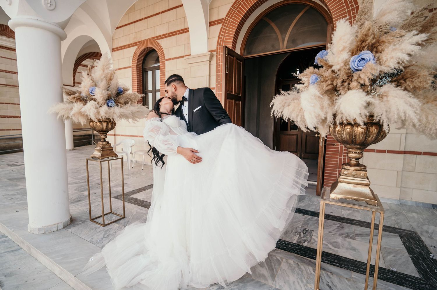 A couple in wedding attire embrace during golden hour with scenic outdoor landscapes in the background.