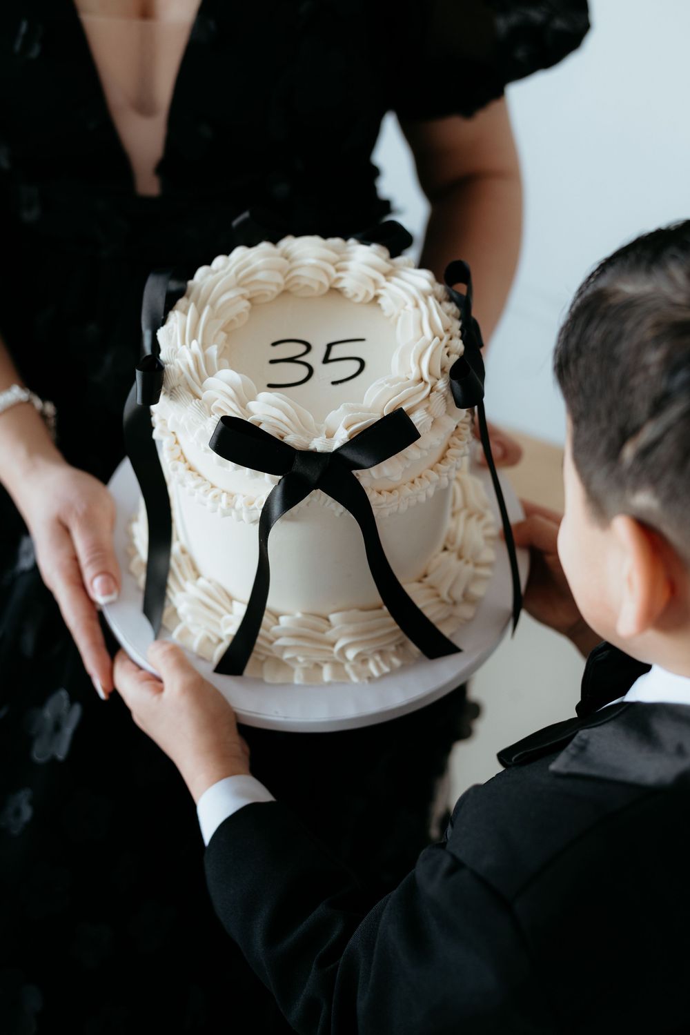 White birthday cake with number 35 and black ribbon being displayed.