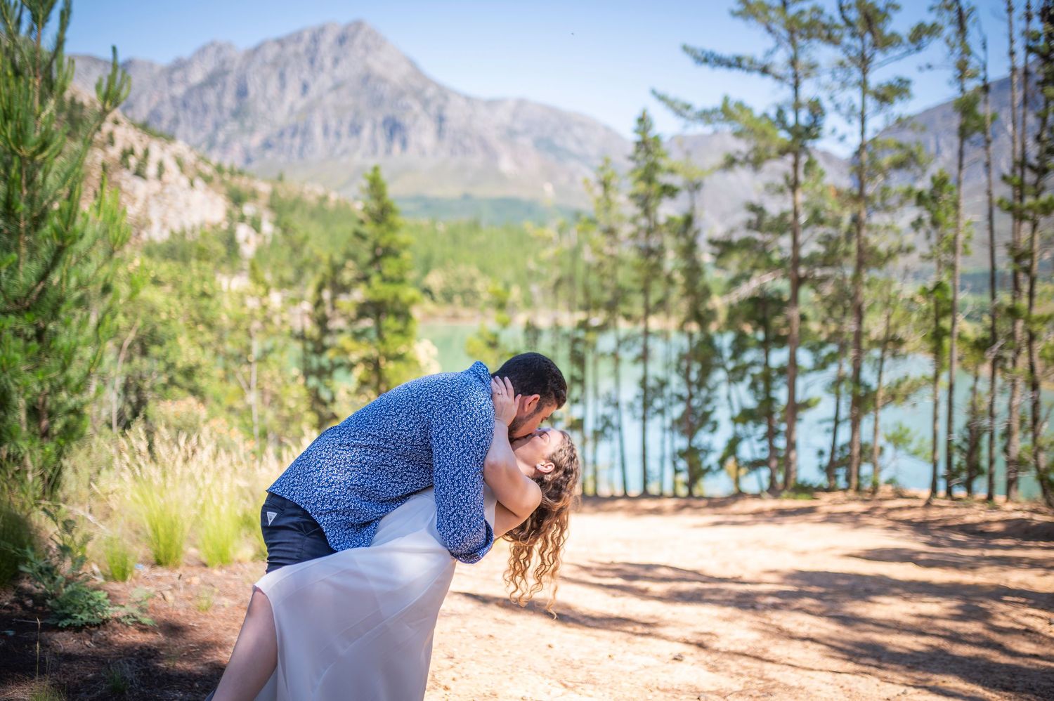A hiker takes in scenic mountain views while trekking through tall pine trees in rugged wilderness terrain.
