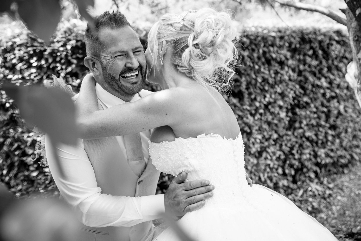 A happy couple shares joyful embraces during a candlelit wedding celebration in a garden setting.