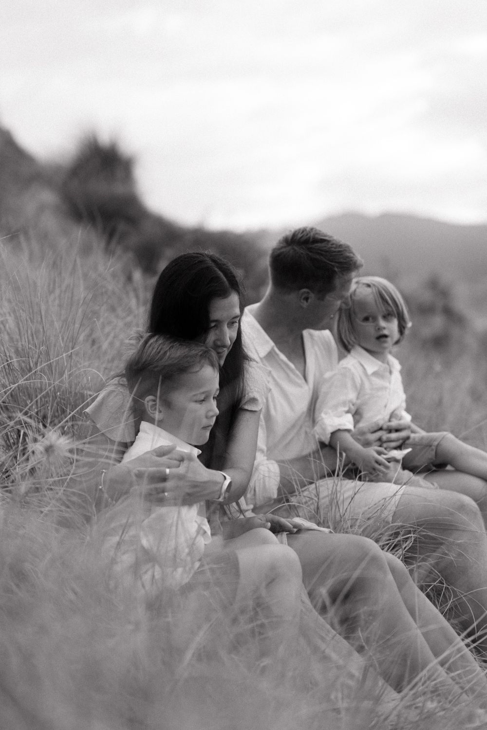 Black and white photo of children laughing together while resting in tall grass.