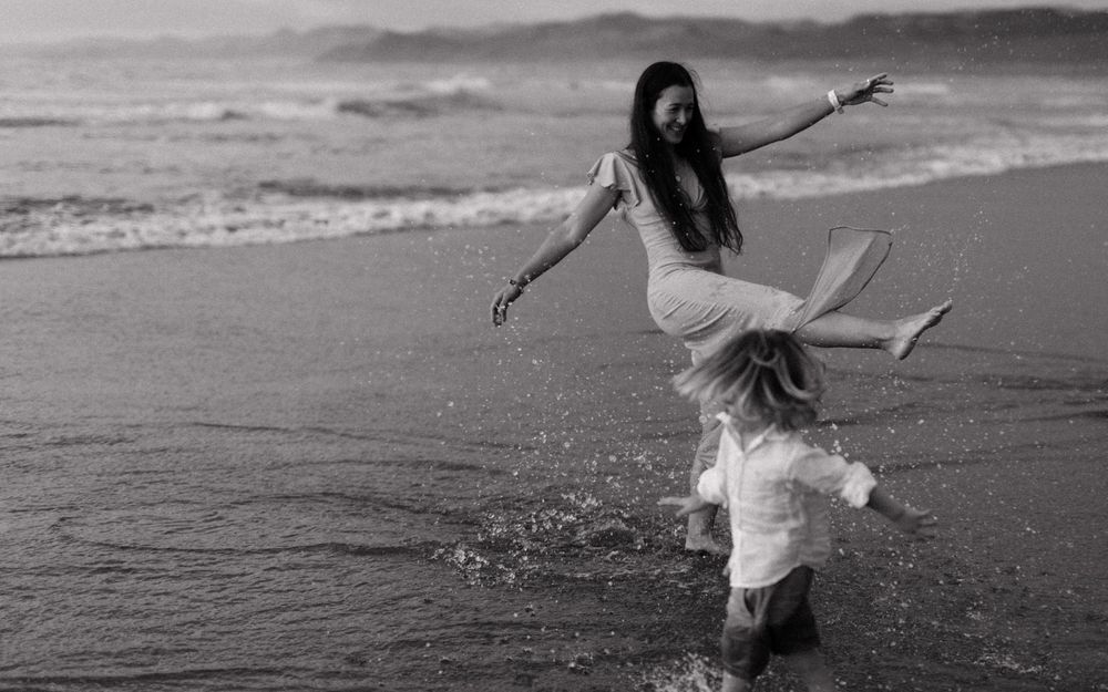 Family members running and playing joyfully along the beach at sunset.