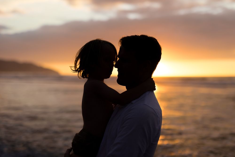 Romantic silhouettes against a golden sunset over the ocean.