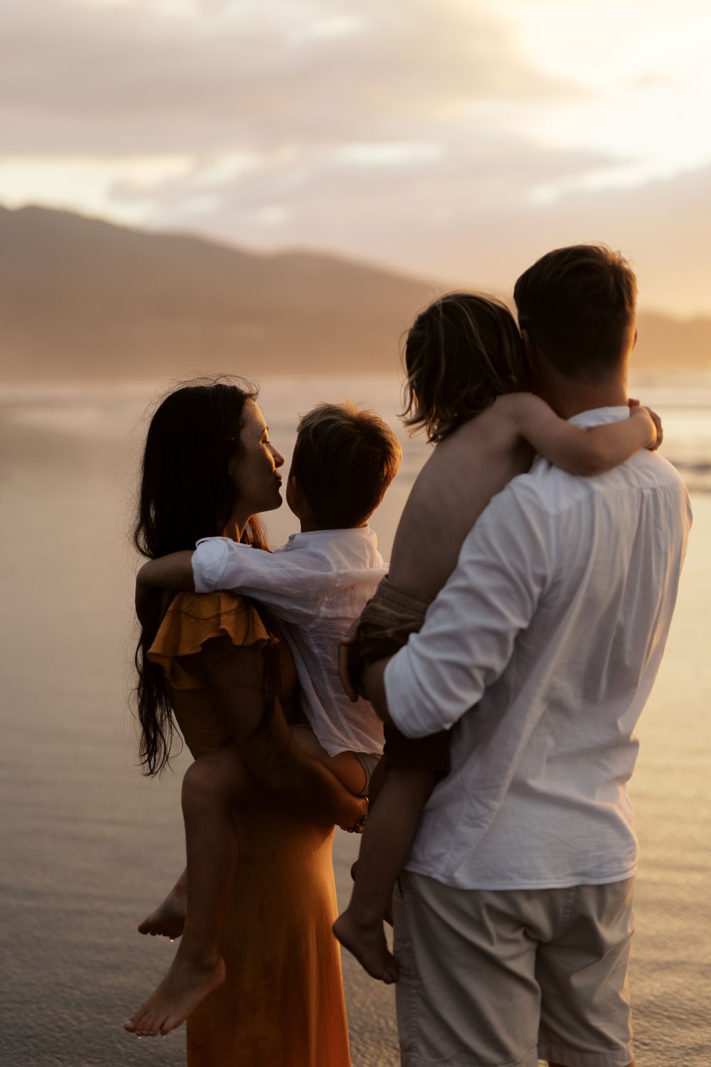 Family sharing tender moments together on the beach at sunset.