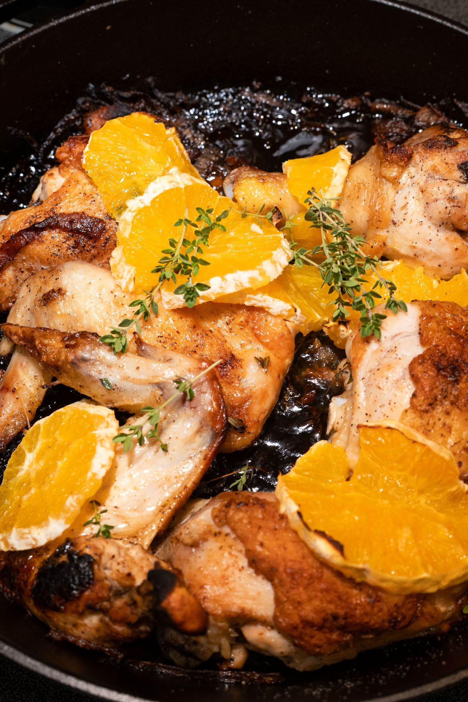 Pan-seared chicken with fresh oranges and herbs in a cast iron skillet.