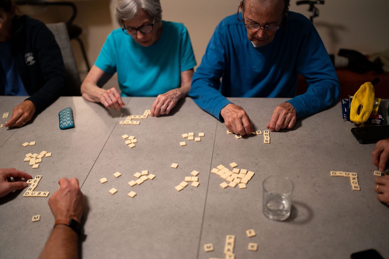 People playing dominoes or board game on dark table during evening gathering.