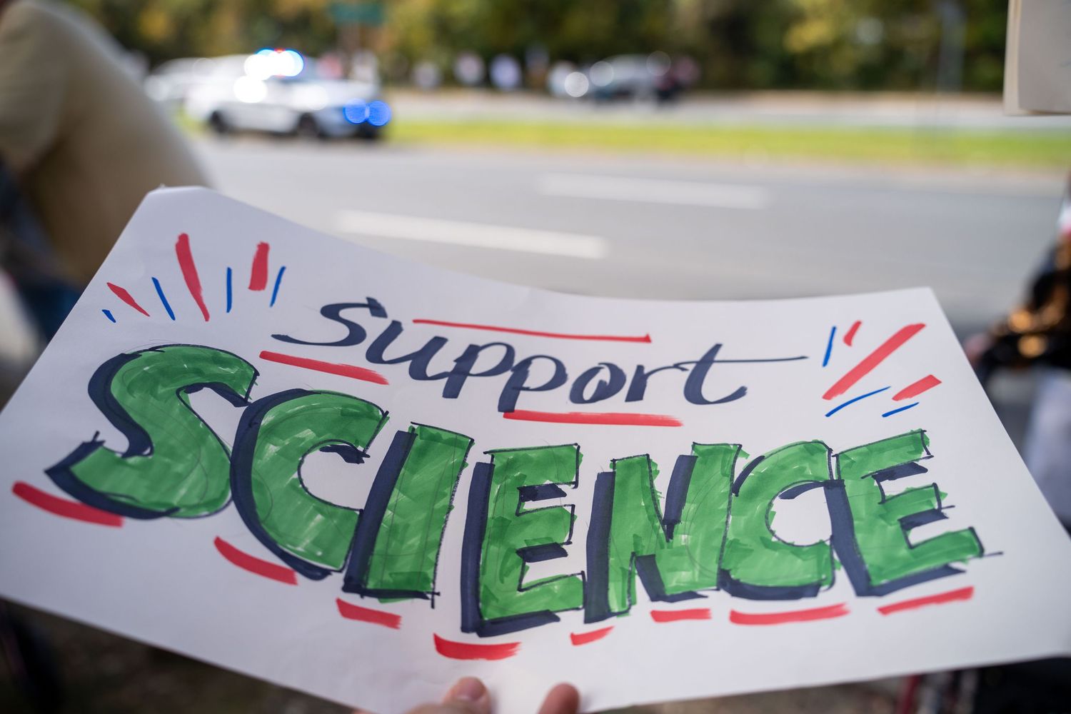 Hand-drawn protest signs supporting science displayed in sequence outdoors.
