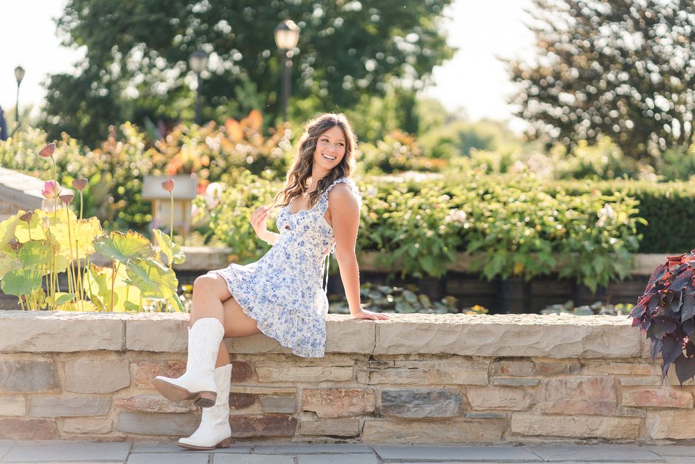 A floral dress photoshoot on a stone wall in an outdoor garden setting.
