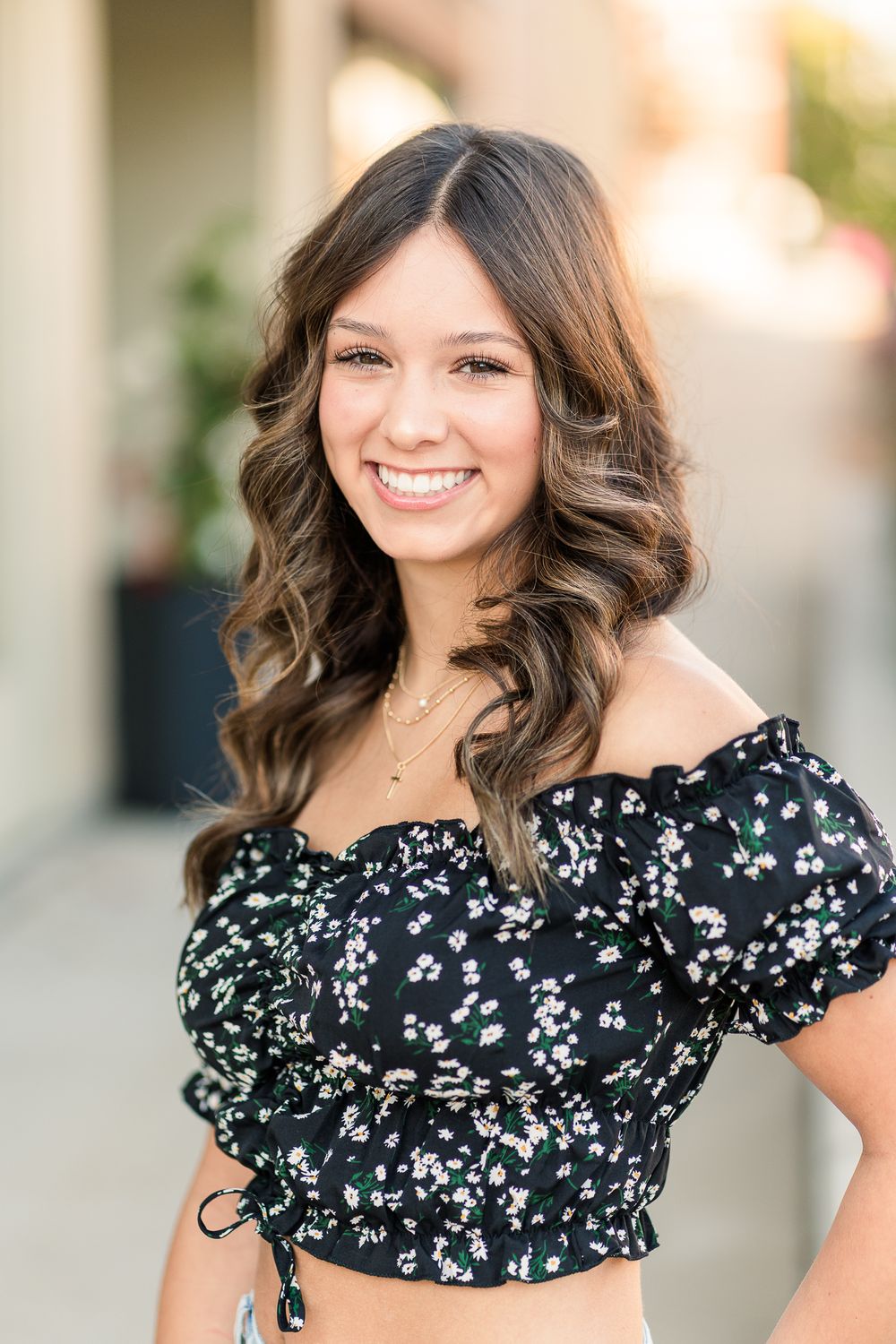 A portrait in a black floral crop top with puff sleeves against a light background.