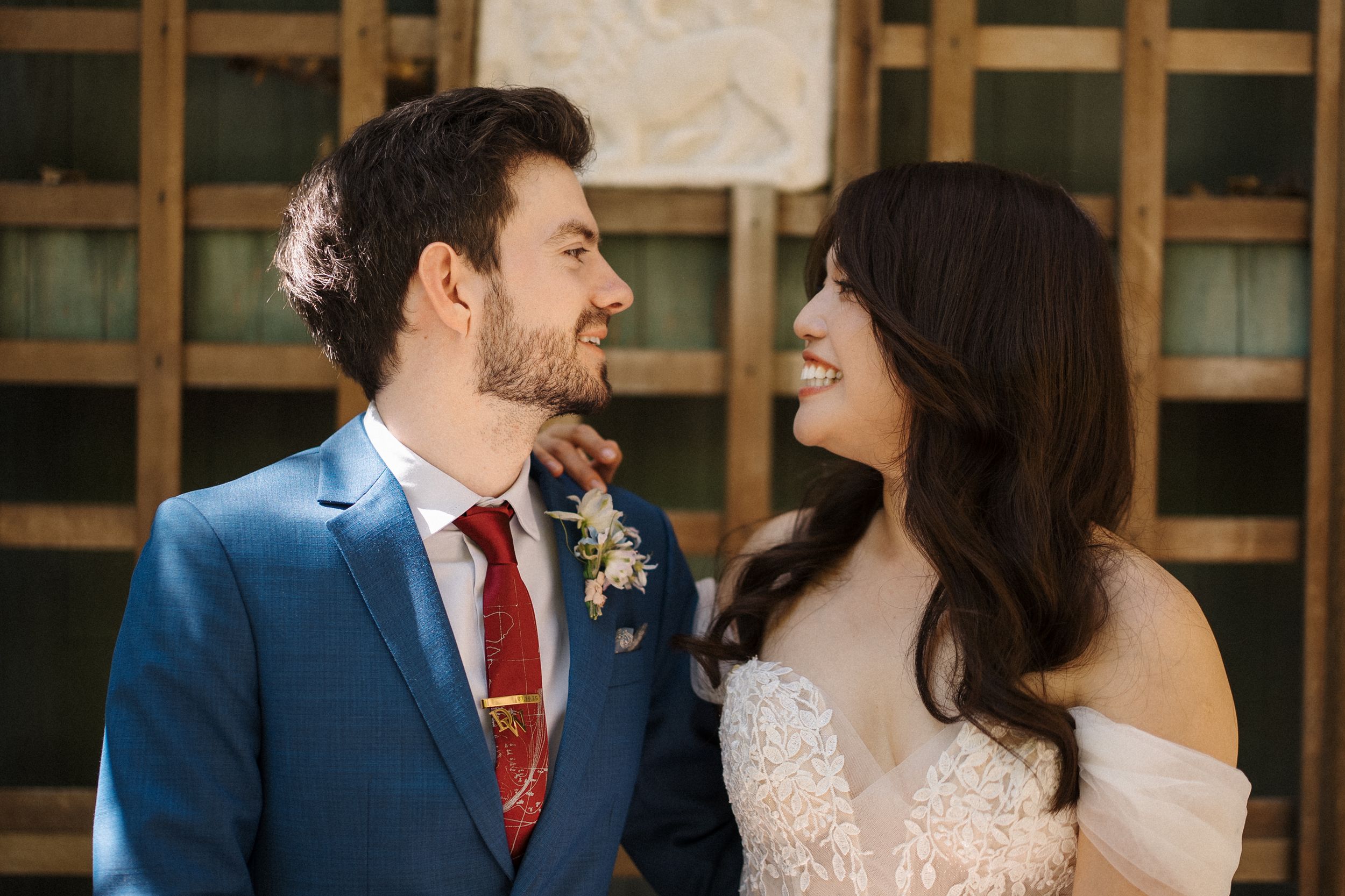 Couple in elegant wedding attire gazes lovingly at each other during their special day.