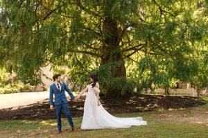 A romantic couple shares intimate moments in a serene garden setting with sunlight filtering through trees.