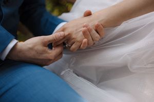 Close-up of hands adjusting a white fabric on a work surface while crafting or sewing.
