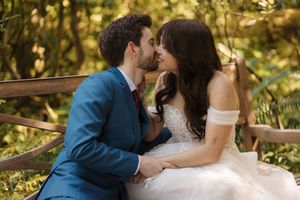A couple in wedding attire share romantic moments in a sun-dappled garden setting during golden hour.