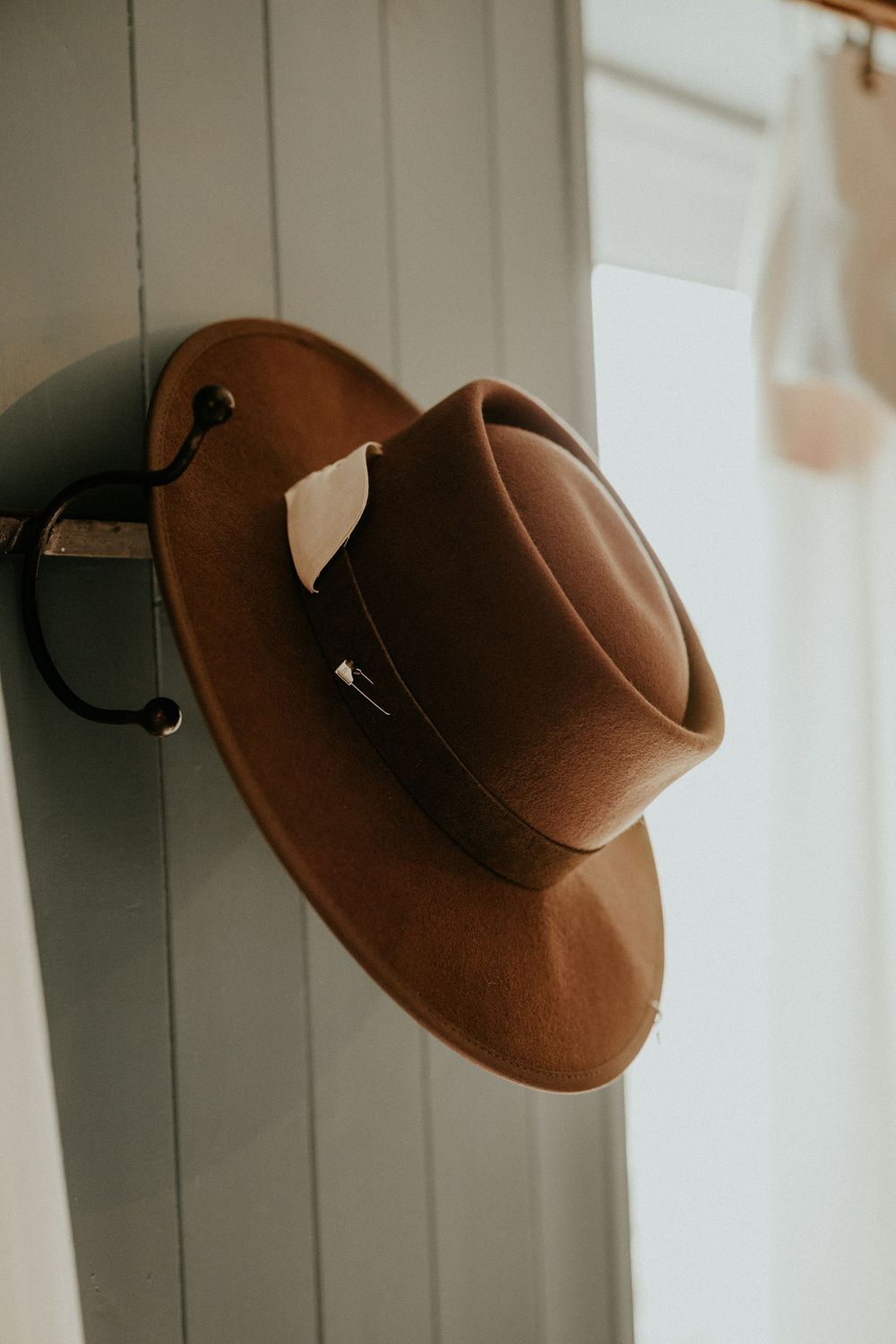 A brown felt cowboy hat hangs on a white wall hook in progressive artistic angles across multiple frames.