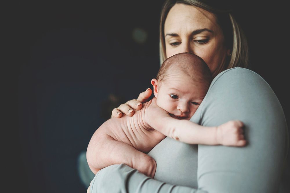 Parent and newborn baby sharing tender moments during professional photo session.