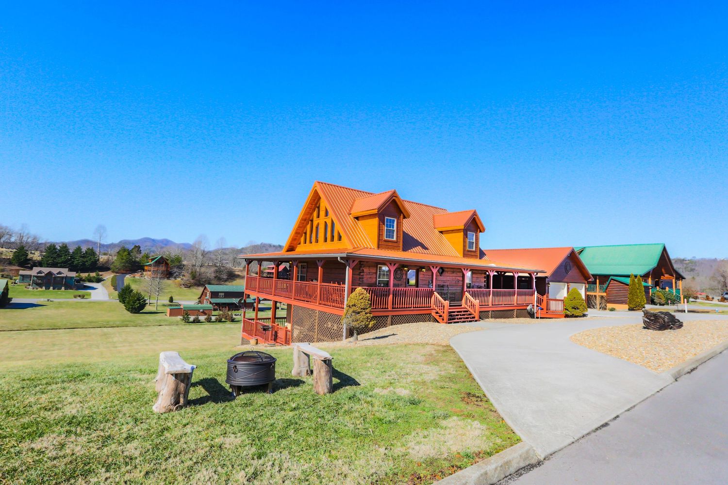 Panoramic view of colorful rustic cabins and lodges nestled in a rural mountain setting against a bright blue sky.
