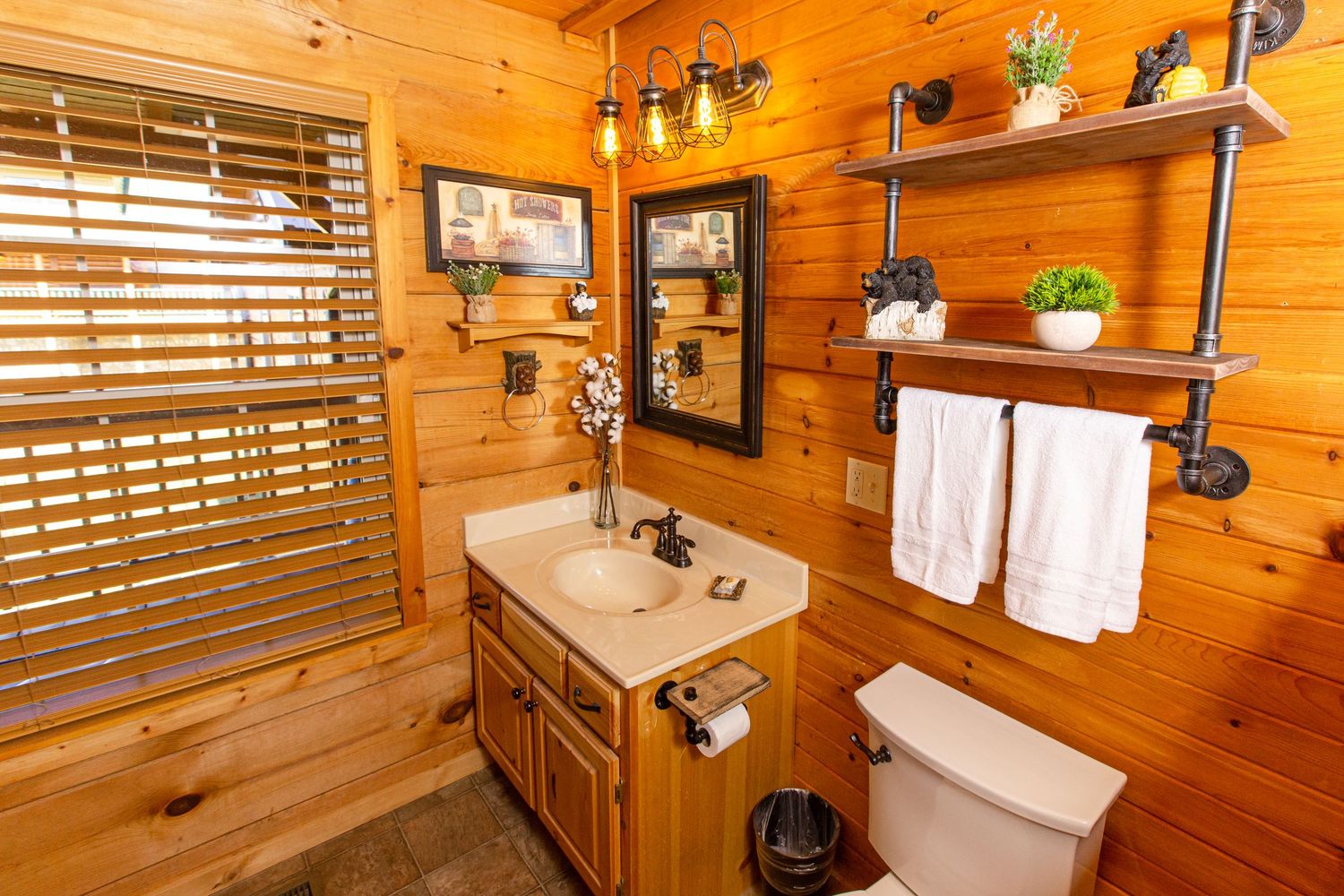 Rustic bathroom with wood walls, white fixtures, and natural light streaming through window blinds.