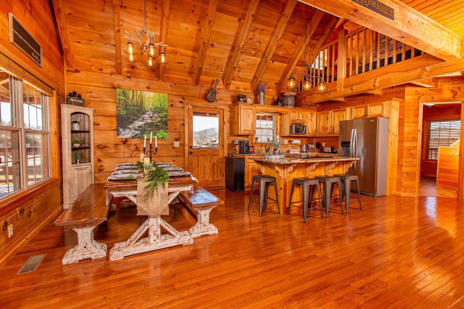 Open concept log cabin interior with vaulted ceilings and natural wood finishes throughout.