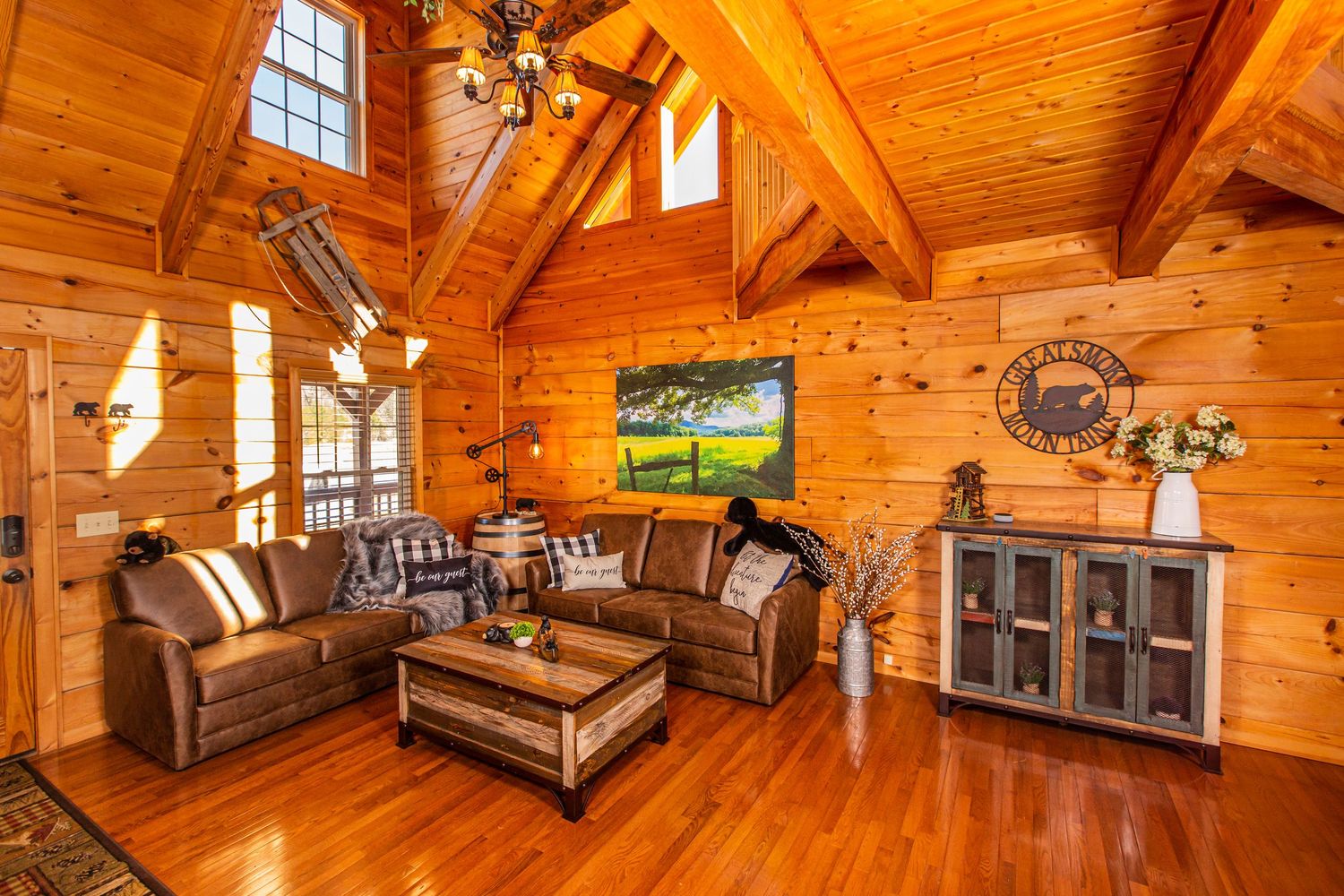 Rustic log cabin interior with warm wood paneling, cathedral windows, and cozy bedroom loft space.