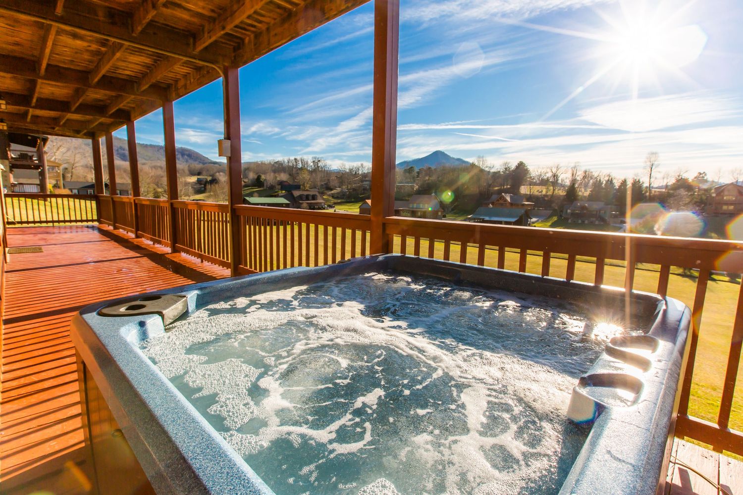 Hot tub on covered deck with panoramic mountain views and blue skies.