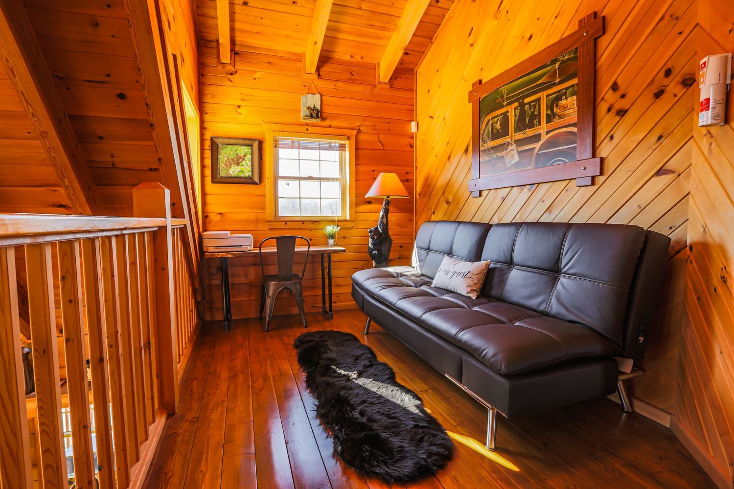 Cozy wood-paneled cabin interior with dark leather couch and warm lighting showcasing rustic mountain lodge ambiance.