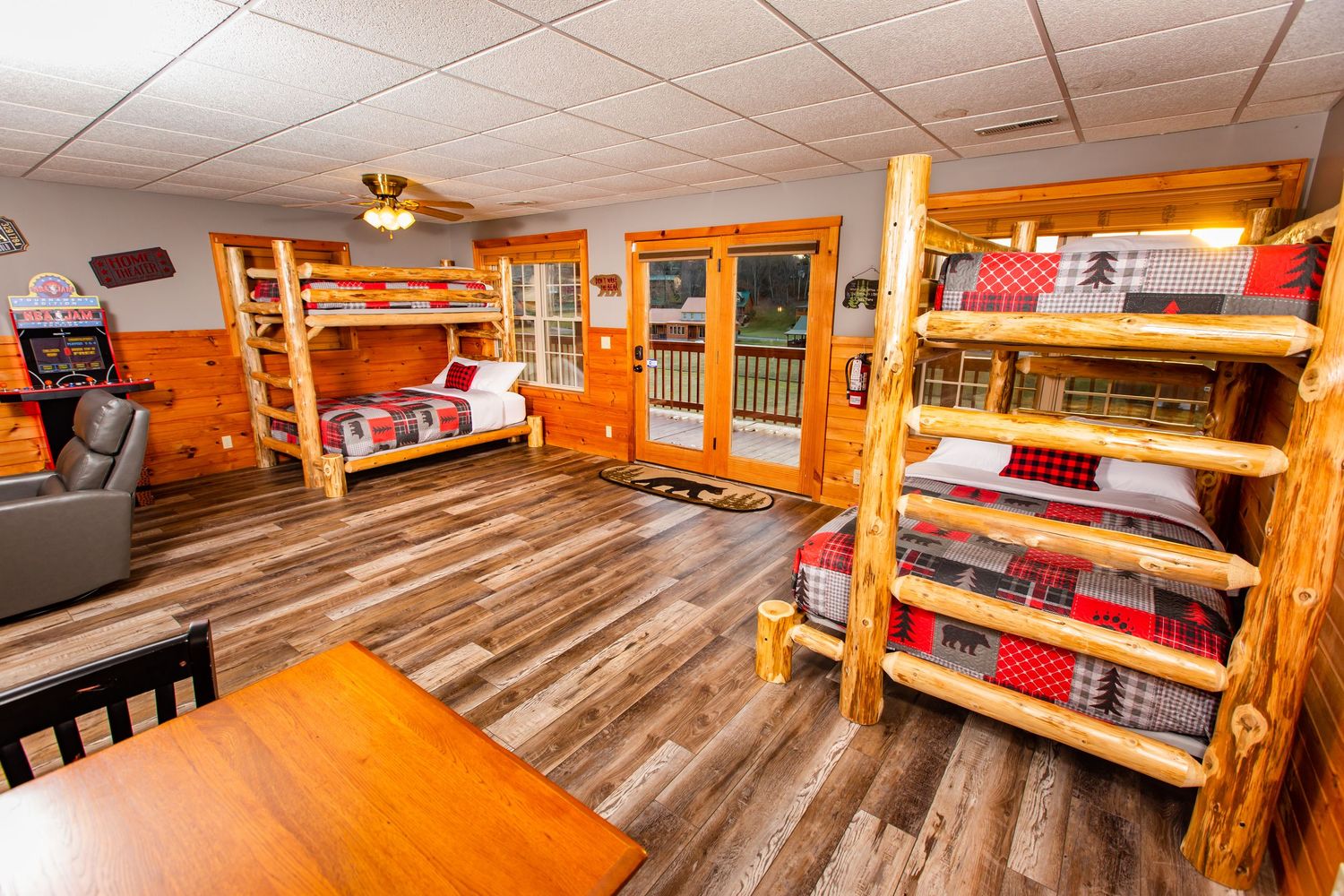 Game room with pool table, entertainment center, and wood-paneled walls in rustic cabin setting.
