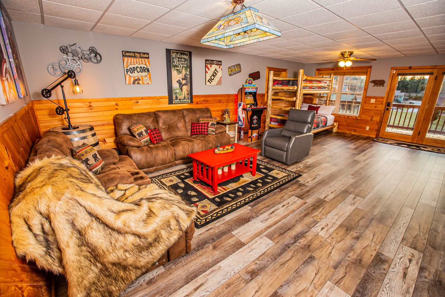 Game room with vintage arcade machines, pool table, and rustic log cabin interior design.
