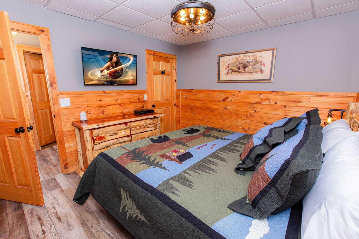 Cozy cabin bedroom with blue walls, pine trim, and comfortable bedding in natural light.