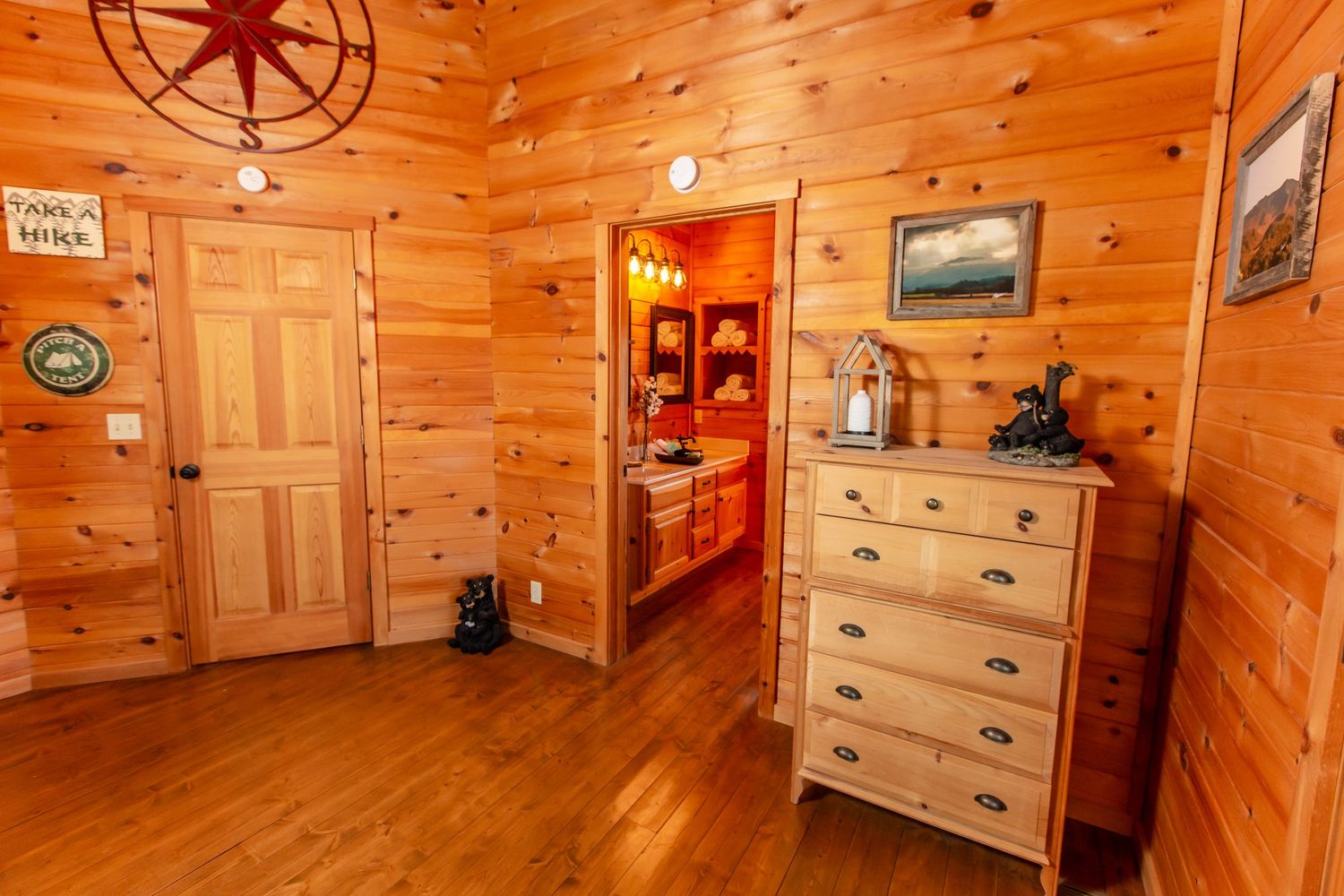 Rustic log cabin interior with wood-paneled walls, compass wall decor, and warm lighting creating a cozy atmosphere.
