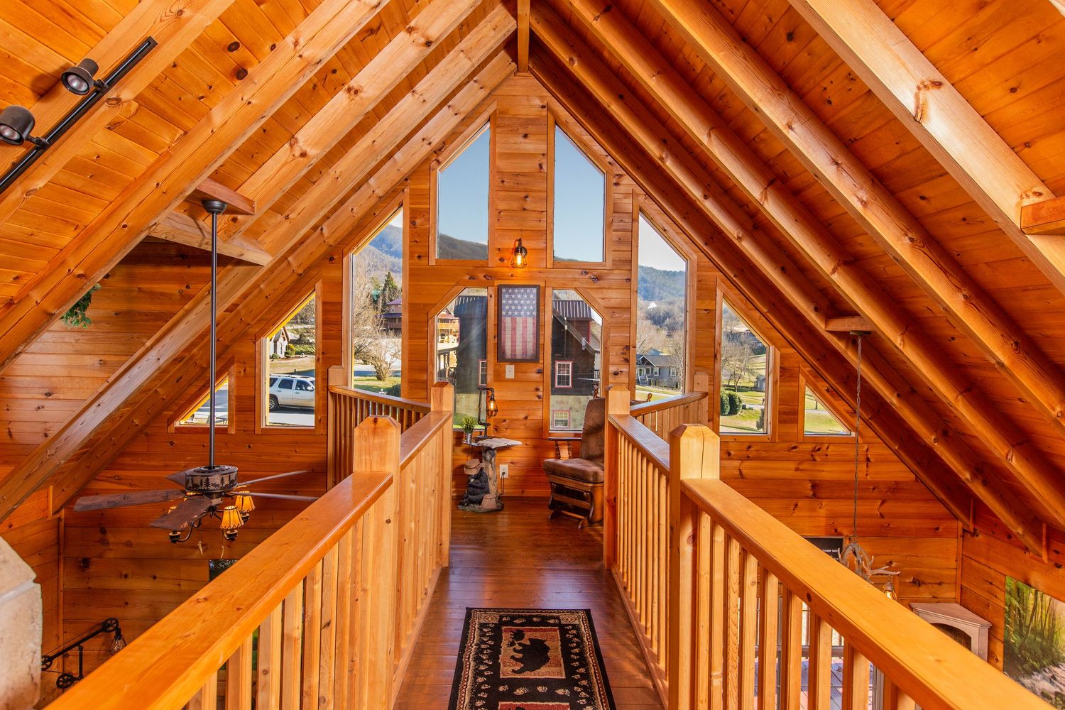 Rustic wooden staircase and hallway with natural pine walls and ceiling beams in a cozy cabin interior.