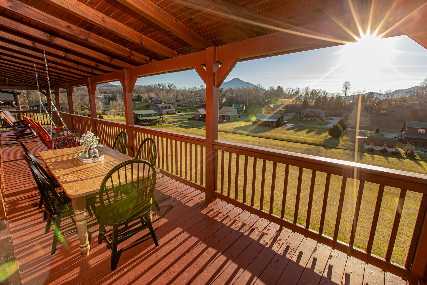 Panoramic view of rolling hills and mountains from a wooden deck with rocking chairs.