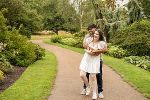 A couple walks together on garden paths surrounded by lush greenery.